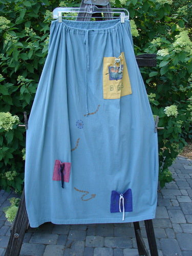 1996 Destination Skirt Travel by Path Sea Spray Size 2: A blue skirt with a patchwork design, drawstring waist, painted pockets, and a widening bell shape.