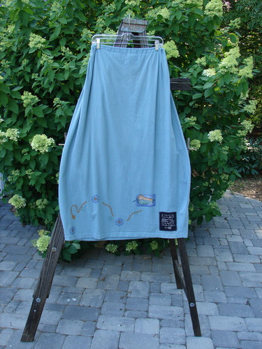 1996 Destination Skirt Travel by Path Sea Spray Size 2: A blue skirt with a full drawstring waistline, painted pockets, and a widening lower bell shape.