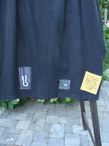 1996 Destination Skirt: Black cloth with patches, wooden post, stone walkway, stone floor. Full drawstring waistline, 3 painted pockets, Blue Fish patch, widening lower bell shape. Terrific flare, tons of pockets. Waist 26-48, hips 56, length 38.
