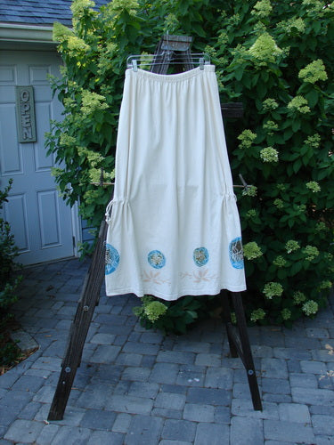 1999 Tie In Skirt Leaf Medallion Natural Size 2: A white skirt with leaf medallion theme paint, featuring a full elastic waistband and draw cords.
