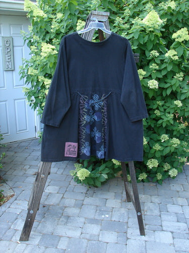 A 1997 Jester's Dress Moon Celtic Obsidian Size 2. A black shirt on a wooden stand with a close-up of fabric.