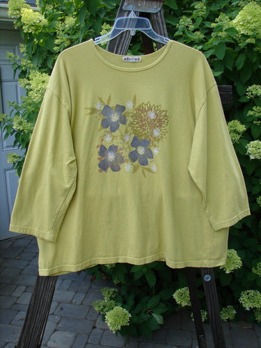 Barclay Long Sleeve Tee Multi Floral Citron Size 2: A wide, generous shape with three-quarter length sleeves. Features a sunny, cheerful floral theme on a yellow shirt with flowers.