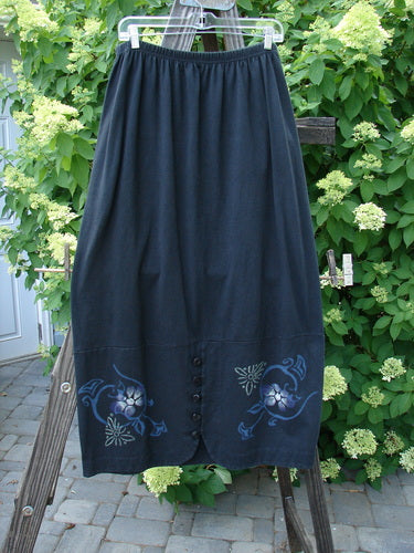 1997 Indra Skirt with whimsical florals, elastic waistline, double paneled lower, colorful chiseled buttons, deep side pockets, and superior vents with loop closures. Size 2, obsidian color.
