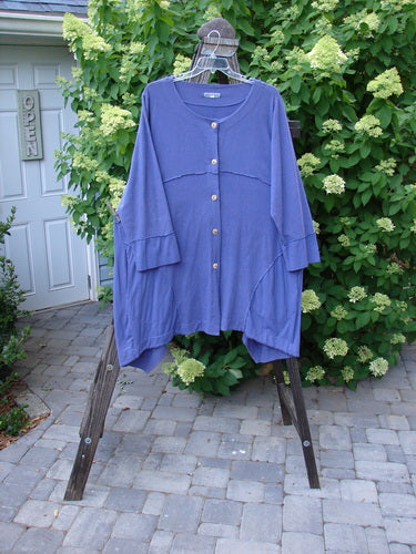 Image: A blue shirt on a rack with a sign on a door and a blue sheet under a cloth.

Alt text: Barclay Hemp Cotton Two Tier Sectional Jacket on display with other clothing items.