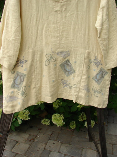 1999 Linen Antique Top Garden Plantain Size 1: A white shirt with a design on it, featuring a fancy garden theme paint. Vented sides, hidden pockets, and a rounded V neckline. Made from medium weight linen.