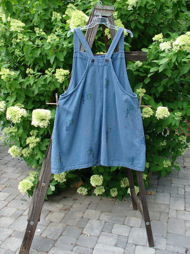 Barclay Canvas Urban Pocket Apron Jumper Mosaic Chair Blue Jean Size 1: A blue jean overalls with tear button accents, fixed shoulder straps, and two drop front pockets.