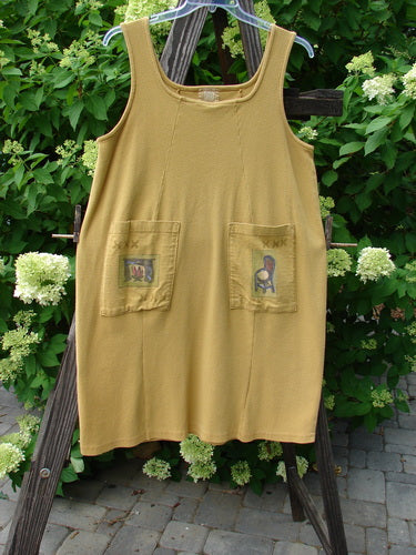 1999 Square Rib Pinafore Jumper in Gold, Size 1: A yellow dress with pockets on a wooden stand, perfect for a cozy home.