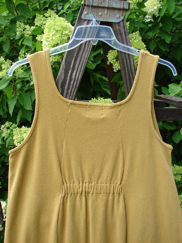 1999 Square Rib Pinafore Jumper Home Gold Size 1: A yellow dress on a swinger with a plastic swinger on a wooden stand