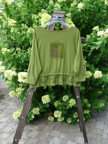 A green shirt with a pattern on it, hanging on a clothes rack.