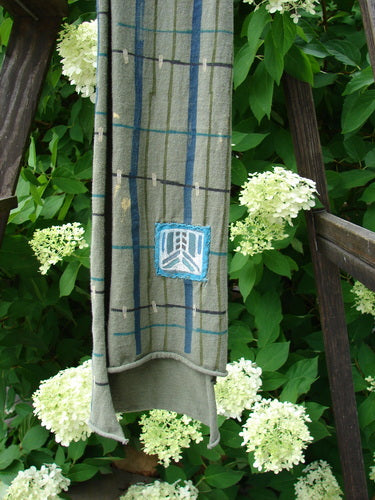 Barclay Patched Scarf, a cloth from a wooden ladder. Close-up of a towel, bench, and blue/white logo patch on fabric. Outdoor, flower, plant, hydrangea, garden.