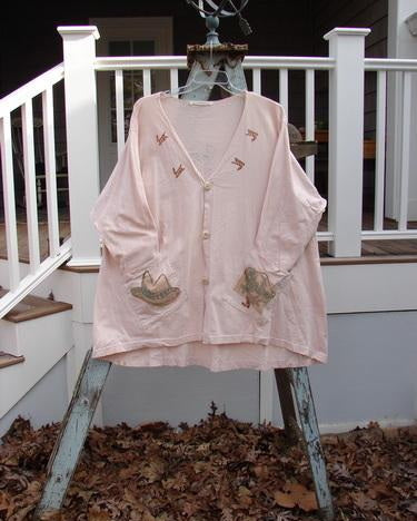 1996 Triangle Cardigan Cowboy Dune OSFA: A pink cardigan with a hat on it. Features include a deep V neckline, angled front pockets, and a signature Blue Fish stamp.