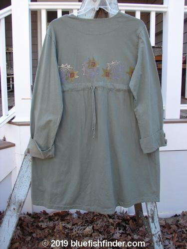 2000 Puzzle Jacket Star Eucalyptus Size 1: A long-sleeved dress with a floral design on a swinger. Cuffed and tabbed lower button sleeves, deep V-shaped neckline, and tiny front accent pockets. Drawstring back and varying hemline.