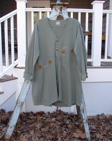 2000 Puzzle Jacket Star Eucalyptus Size 1: Long-sleeved shirt with flower design on a ladder. Cuffed and tabbed lower button sleeves, deep V-shaped neckline with two-button closure. Features front accent pockets, drawstring back, and varying hemline. Made from organic cotton.