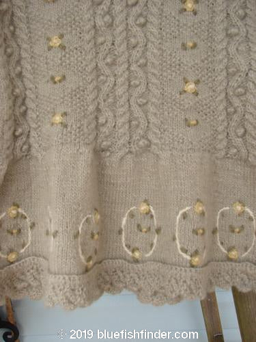 Close-up of a Tara Handknits NWT Kids Wild Smock Sweater Jacket, size Medium. Highly detailed with bright and blended patterns, lace collared neckline, and knit accents. Features oversized round metal buttons, front pockets, and empire waist flounce. Luxurious and collectible.