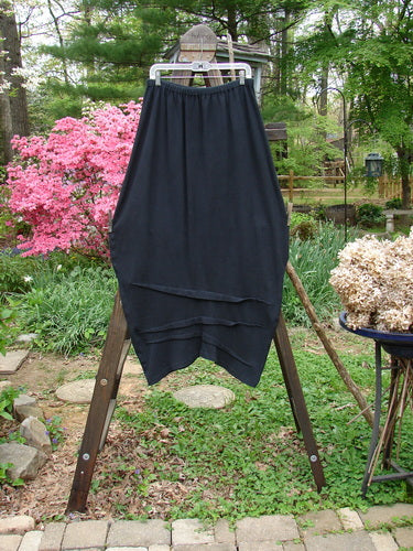 2000 Thermal Awen Skirt on wooden rack, close-up of plant and pole. Generous bell shape, textured diagonal hemline. Size 2.