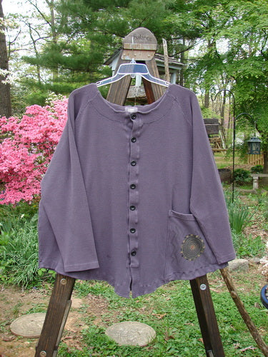 2000 Thermal Moonlight Cardigan Jacket Pinwheel Eggplant Size 2: Swingy purple shirt on wooden stand, detailed with oversized front pocket, rounded hemline, and rear pleats for superior back swing.