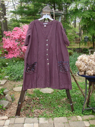 Barclay Linen Double Tie Back Jacket Honeycomb Maroon Size 2: A purple dress on a clothes rack with exterior vertical stitchery and front drop flop pockets.