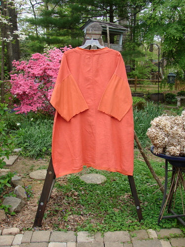 Image alt text: Barclay NWT Linen Cotton Sleeve Pocket Cardigan in Clementine, Size 2. Unpainted. Orange shirt and dress on rack, close-up of plant and bicycle wheel.